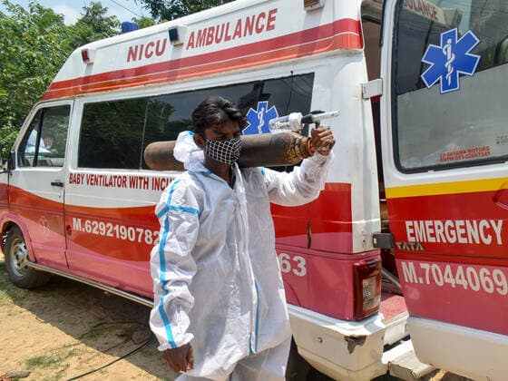 India: The ambulance man in Kolkata Babu a member of the Amit Sardar team is carrying an Oxygen cylinder to load an ambulance before pickup a Covid patient. Amit Sardar, 35, a physically challenged person, who is helping others in this crisis period of covid-19 pandemic in Kolkata. He with his two Co workers Sanjay and Babu effortlessly is providing ambulance service door to door for the covid-19 patients as much as lower cost and some time it s free. Kolkata West Bengal India Copyright: SudiptaxDas