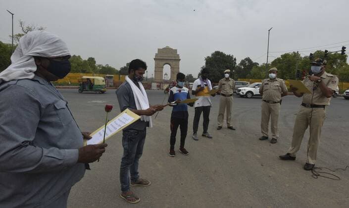 NEW DELHI, INDIA - MAY 23: Delhi police officer offer flowers to people who stepped out of their homes during lockdown and requested them to stay indoor and follow covid guidelines At India Gate on May 23, 2021 in New Delhi, India. Police also distributed masks and sanitizers to the violators. Delhi reported 1649 new cases of COVID on May 23.(Photo by Sonu Mehta Hindustan Times) Delhi Police Give Roses To Lockdown Violators