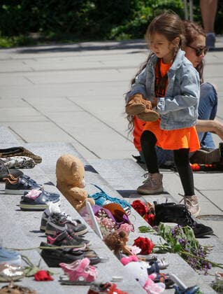 (210530) -- VANCOUVER, May 30, 2021 -- A girl tries to put a pair of shoes on the staircase while attending a memorial event for the 215 children whose remains have been found buried at a former Kamloops residential school outside Vancouver Art Gallery in Vancouver, British Columbia, Canada, May 29, 2021 . The reported discovery of the remains of 215 indigenous children at a former residential school in Kamloops in western Canada has shocked Canadian people. In a press release on Friday, the British Columbia Assembly of First Nations said it is grieving the location of the 215 children. (Photo by Xinhua) CANADA-VANCOUVER-KAMLOOPS INDIGENOUS SCHOOL-CHILDREN REMAINS-MEMORIAL LiangxSen 