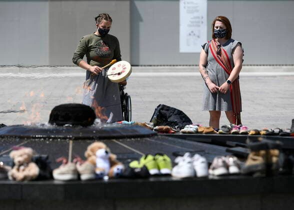 May 30, 2021, Ottawa, on, Canada: Jordyn Hendricks, left, and their sister Marissa, right, drum and sing the Traveling Song at the Centennial Flame on Parliament Hill in Ottawa, where shoes were placed to symbolize the 215 children whose remains were found at the grounds of the former Kamloops Indian Residential School at Tkâ€⠢emlups te Secwo pemc First Nation in Kamloops, B.C., on Sunday, May 30, 2021, Ottawa Canada - ZUMAc35_ 20210530_zaf_c35_046 Copyright: xJustinxTangx