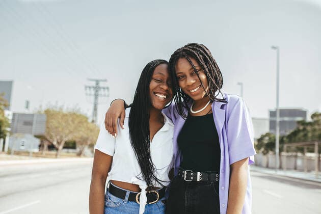 Creative Highlights Symbolbilder Cheerful African American female friends in casual clothes embracing while standing on asphalt road in street with buildings in city Copyright: xDanixNavarrox Model Released