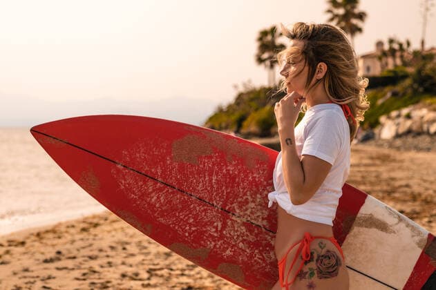 Female surfer with surfboard looking away on sandy coast against palm tree in daytime, Model released, Property released Copyright: xSergioxMenax MR