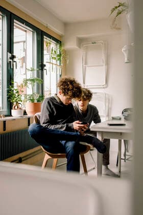 IMAGO Creative: Jahreszeit Winter, Fantasievoll drinnen spielen Brothers sharing mobile phone while siting at table Sweden, Stockholm, model released, property released Copyright: xMaskotx , MA86515