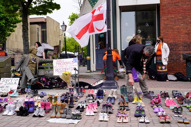 May 31, 2021, CHARLOTTETOWN, PE, Canada: Elder Junior Peter Paul (sitting) uses a feather in a smudging ceremony next to 215 pairs of children s shoes placed in remembrance of the bodies discovered at the Kamloops Indian Residential School in British Columbia in Charlottetown, on Monday, May 31, 2021. CHARLOTTETOWN Canada  - ZUMAc35_ 20210531_zaf_c35_011 Copyright: xJohnxMorrisx