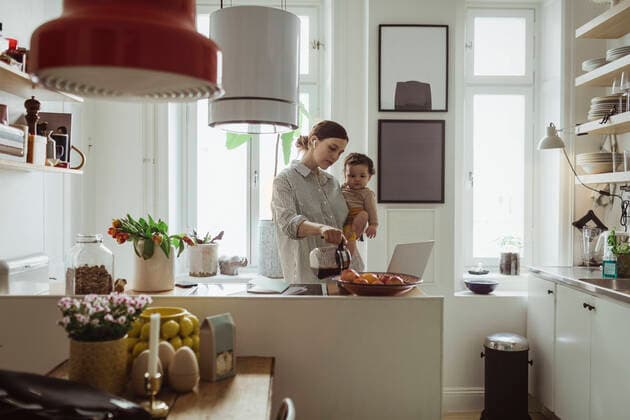 IMAGO Creative, Internationaler Frauenmonat, Entrepreneurinnen Female professional pouring coffee while carrying toddler son in kitchen Sweden, Stockholm, model released, property released Copyright: xMaskotx , MA86822