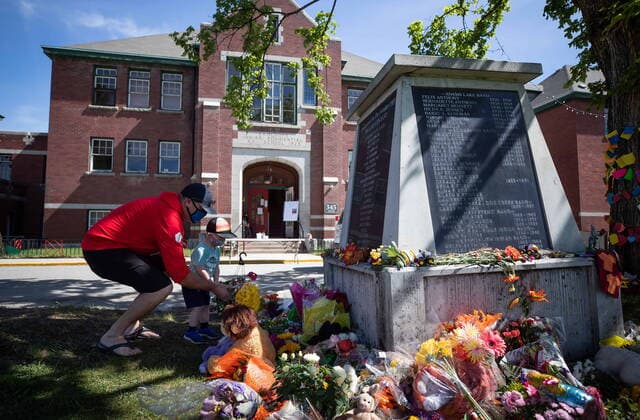 May 31, 2021, Kamloops, BC, Canada: Jaret Hamm and his son John Hamm, 2, place flowers beside a monument outside the former Kamloops Indian Residential School as part of a growing makeshift memorial to honour the 215 children whose remains have been discovered buried near the facility, in Kamloops, B.C., on Monday, May 31, 2021. Kamloops Canada - ZUMAc35_ 20210531_zaf_c35_072 Copyright: xDarrylxDyckx
