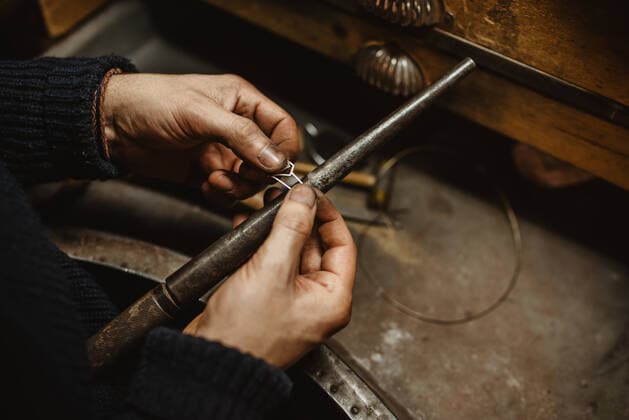 Creative Highlights Symbolbilder Bearded male goldsmith using tongs while making tiny metal detail on workbench in workshop, Model released, Property released Copyright: xAlbertoxMenendezx MR