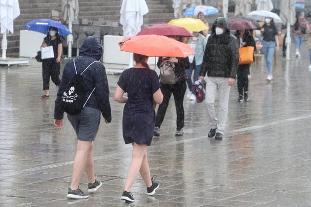 Passers-by walk with umbrellas across the Schlossplatz in downtown Stuttgart during a heavy rainstorm, Baden Württemberg, Germany