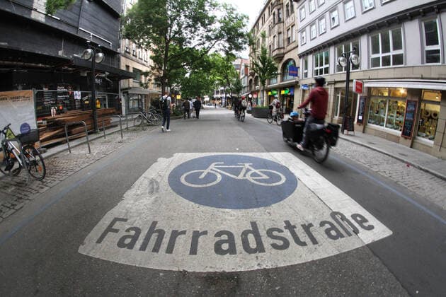 Bicyclist riding in Eberhardstraße, which is declared as a bicycle street with a pictogram, in the city center of Stuttgart, Baden Württemberg, Germany
