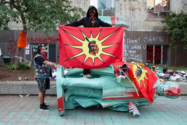 Kanada, Proteste und Sturz der Egerton Ryerson Statue in Toronto June 6, 2021, Toronto, on, Canada: A protester holds a flag over top of the statue of Egerton Ryerson after it was pulled down at Ryerson University, in Toronto on Sunday, June 6, 2021. Ryerson was the chief superintendent of education for Upper Canada and his recommendations were regarded as instrumental in the design and implementation of the Indian Residential School System. Toronto Canada  - ZUMAc35_ 20210606_zaf_c35_101 Copyright: xChrisxYoungx