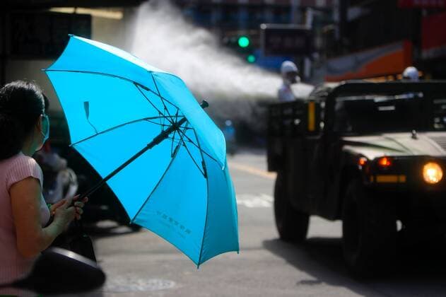 June 12, 2021, New Taipei, New Taipei, Taiwan: A citizen opens an umbrella while chemical troops disinfecting public areas pass by in New Taipei, a zone deeply affected by the community transmission of Covid-19. Taiwan has seen an increasing number of domestic cases and deaths related to the coronavirus while facing an inadequate supply of vaccines. New Taipei Taiwan - ZUMAs313 20210612_zip_s313_004 Copyright: xDanielxCengxShou-Yix