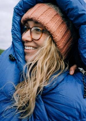 woman smiling in a sleeping bag whilst camping in the Jurassic coast Dorset, England, United Kingdom CR_RABE210614-754260-01 ,model released, Symbolfoto