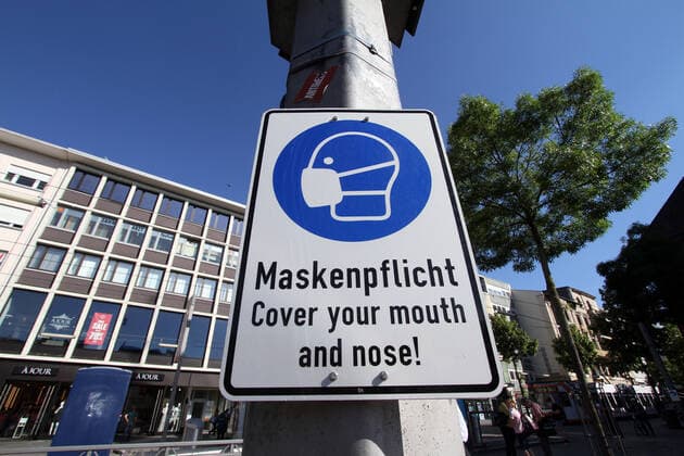 Sign with pictogram and inscription Maskenpflicht hangs on a lamp post at the market place in the city center of Mannheim, Baden Württemberg, Germany