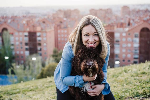Smiling woman with blond hair embracing Spanish Water Dog on grass during sunset model released Symbolfoto property released EBBF03392