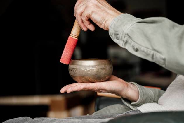 Senior man playing Tibetan singing bowl at home model released Symbolfoto property released AFVF08767