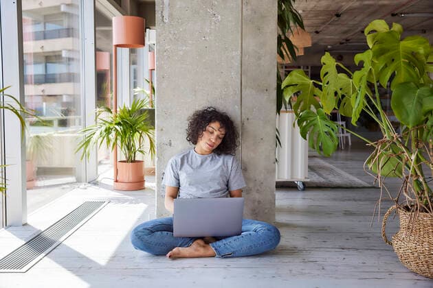 IMAGO Creative: Landleben, Digitalisierung auf dem Land Tired woman with laptop sitting on floor at home apartment model released Symbolfoto property released FMKF07172
