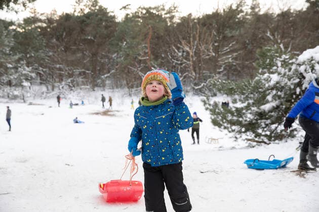 IMAGO Creative: Wintersport, Urlaub Playful boy with toboggan standing on snow model released Symbolfoto FVDF00013