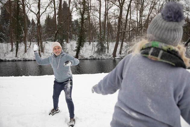 IMAGO Creative: Alternativer Wintersport Man throwing snowball on woman during winter model released Symbolfoto FVDF00104