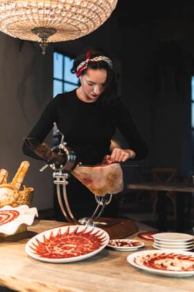 Female owner cutting meat on ham holder at restaurant model released Symbolfoto property released JAQF00556