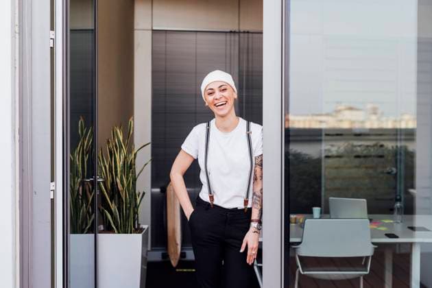 IMAGO Creative: Business - Progressive Geschäftsmodelle Cheerful woman with hands in pockets leaning on office door model released Symbolfoto property released MEUF02622