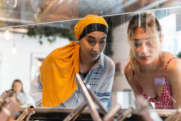 Female friends looking through display cabinet in restaurant model released Symbolfoto property released PNAF01548