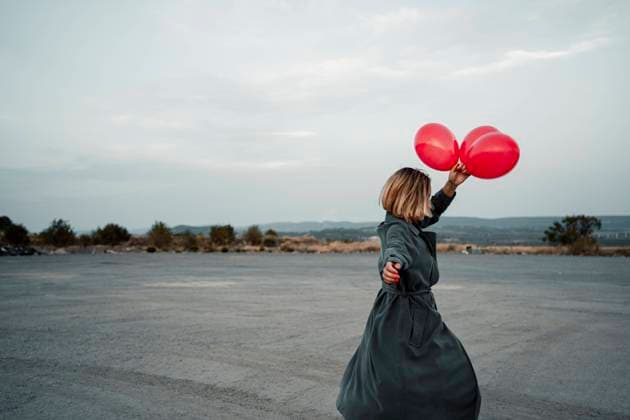 Mid adult woman holding balloon while dancing on road model released Symbolfoto RCPF01007
