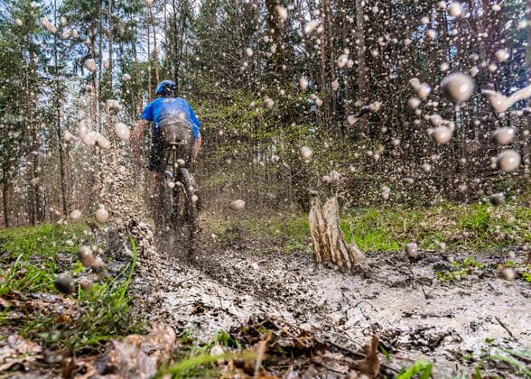 Young man riding mountain bike through mud in forest model released Symbolfoto STSF02944