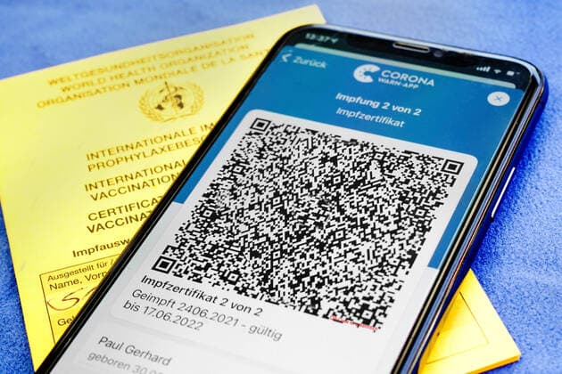 QR code, the digital vaccination certificate in the Corona Warn app on a smartphone confirms a completed vaccination against Covid 19 Lies on the yellow International Vaccination Certificate, Vaccination Card ATTENTION QR code and personal details are made unrecognizable