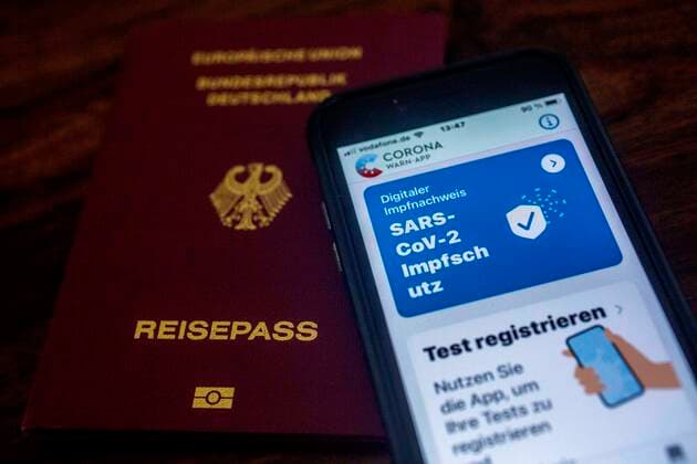 Certificate of double Corona vaccination in the vaccination card and Corona warning on an iPhone and a passport passport vaccination card