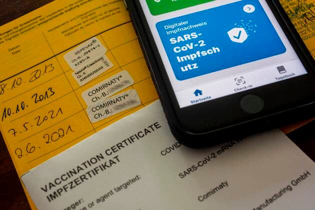 Certificate of a double Corona vaccination in the vaccination card and in the Corona warning on an iPhone vaccination certificate.