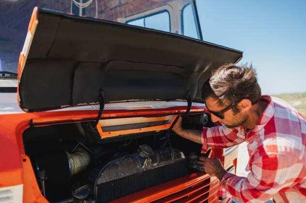Side view of adult unshaven male traveler in casual clothes and sunglasses opening bonnet of retro van parked on sandy road during trip in nature, Model released, Property released Copyright: xCarlosxPintaux MR