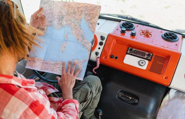 IMAGO Creative: Retro-Revival IMAGO Creative: Digitale Welt, Verzicht auf Technologie From above crop young male traveler in checkered shirt reading map while sitting in retro van during trip in in semi desert valley on sunny day, Model released, Property released Copyright: xCarlosxPintaux MR