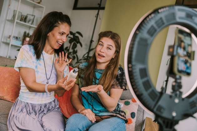 Female influencers holding beauty product while vlogging at home model released Symbolfoto property released MFF08055