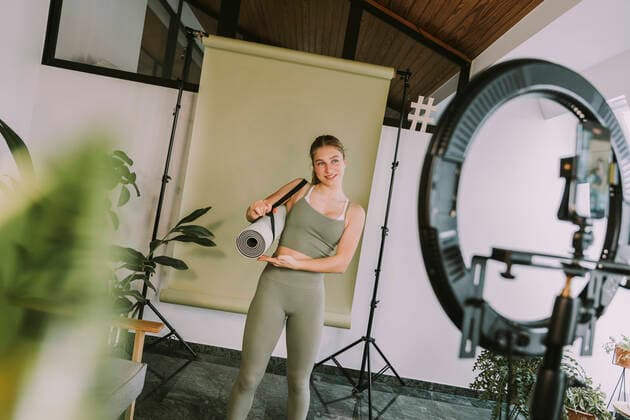 Female fitness trainer showing exercise mat while vlogging at home model released Symbolfoto property released MFF08101