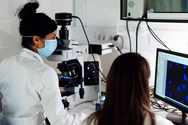 Female scientists working together while examining medical samples on computer in laboratory during COVID-19 model released Symbolfoto property released PGF00584