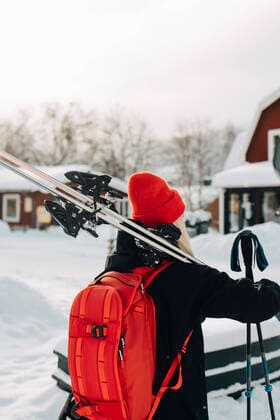 IMAGO Creative: Wintersport, Mode Rear view of young woman wearing red backpack carrying skis Sweden, ?re, model released Copyright: xMaskotx , MA87052