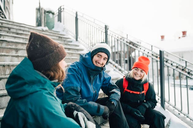 IMAGO Creative: Wintersport, Mode Smiling male and female friends talking while sitting on steps Sweden, ?re, model released Copyright: xMaskotx , MA87053