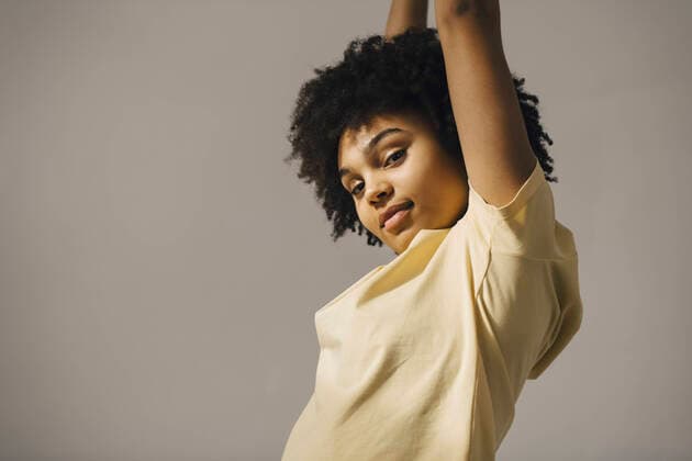 Creative Highlights Symbolbilder Portrait of curly haired woman with arms raised against beige background Sweden, Gothenburg, model released Copyright: xMaskotx , MA87340