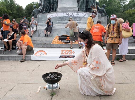 July 1, 2021, Montreal, PQ, Canada: A woman places tobacco into a fire during a gathering and march to honour Indigenous children, denounce genocide and demand justice for residential school victims in Montreal, Thursday, July 1, 2021. Montreal Canada  - ZUMAc35_ 20210701_zaf_c35_211 Copyright: xGrahamxHughesx
