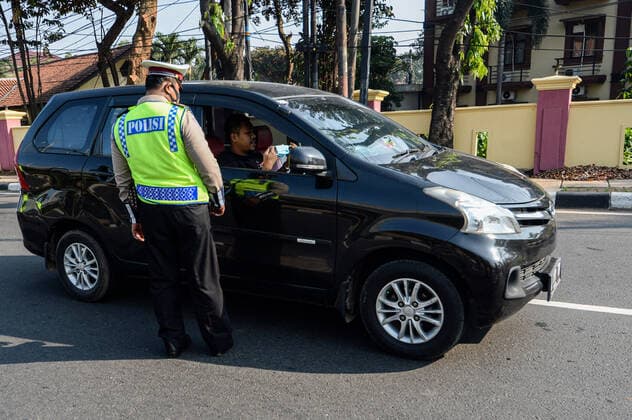 (210703) -- JAKARTA, July 3, 2021 -- A police officer asks a man to put on a face mask on his car in Jakarta, Indonesia, July 3, 2021. The Indonesian government has decided to deploy 53,000 personnel for emergency community activity restrictions (locally known as PPKM) to be imposed in Java and Bali from July 3 to 20, a senior police officer said on Friday. ) INDONESIA-JAKARTA-COVID-19-RESTRICTIONS AgungxKuncahyaxB. 