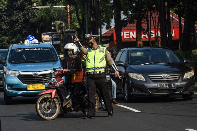(210703) -- JAKARTA, July 3, 2021 -- A police officer asks a man without a proper face cover to pull over to the side of the road in Jakarta, Indonesia, July 3, 2021. The Indonesian government has decided to deploy 53,000 personnel for emergency community activity restrictions (locally known as PPKM) to be imposed in Java and Bali from July 3 to 20, a senior police officer said on Friday. ) INDONESIA-JAKARTA-COVID-19-RESTRICTIONS AgungxKuncahyaxB. 