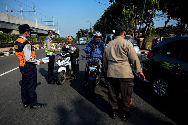 (210703) -- JAKARTA, July 3, 2021 -- A police officer gives a face mask to a man in Jakarta, Indonesia, July 3, 2021. The Indonesian government has decided to deploy 53,000 personnel for emergency community activity restrictions (locally known as PPKM) to be imposed in Java and Bali from July 3 to 20, a senior police officer said on Friday. ) INDONESIA-JAKARTA-COVID-19-RESTRICTIONS AgungxKuncahyaxB. 