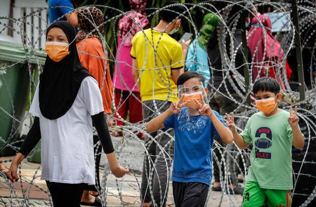 July 3, 2021, Kuala Lumpur, Malaysia: Kids wearing masks walk near a barbed wire after the Covid-19 swab test at the Segambut Dalam housing area which was placed under the enhanced movement control order (EMCO) due to surge in the number of COVID-19 daily cases recorded..Malaysia government starts to further tighten the movement control and imposes lockdown in state of Selangor and parts of Kuala Lumpur, due to the daily high number of coronavirus infections cases reported. Kuala Lumpur Malaysia - ZUMAs197 20210703_zaa_s197_009 Copyright: xWongxFokxLoyx
