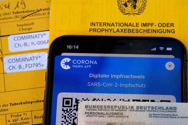 The proof The digital Corona vaccination certificate on the smartphone with the identity card and the vaccination booklet Siegsdorf Bavaria Germany Copyright: xRolfxPossx