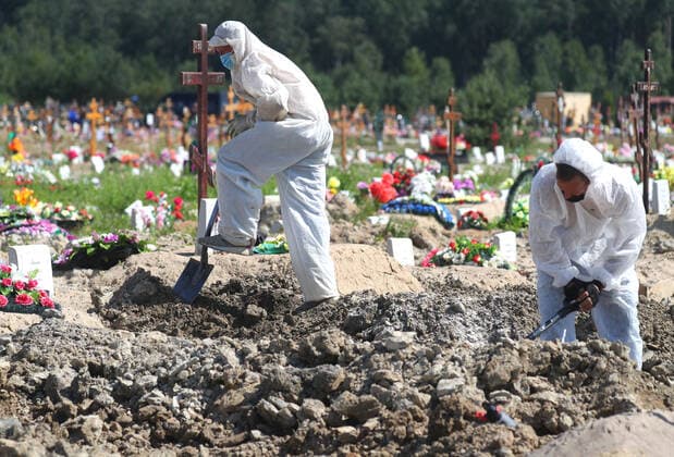 ST PETERSBURG, RUSSIA - JULY 5, 2021: Workers in protective suits are seen during a funeral of deceased COVID-19 patients at the Novoye Kolpinskoye cemetery. Peter Kovalev TASS  TS10732E