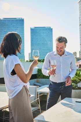Designer and workmate after work having relaxing time in a terrace next to office buildings, they are having a cup of white wine Copyright: xLuisxGomezx Model Released