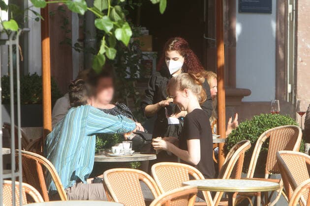 A waitress at a restaurant in downtown Heidelberg collects the check at a full table, Baden Württemberg, Germany
