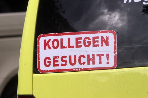 Sticker with the inscription Colleagues wanted is stuck on the back window of an ambulance in downtown Heidelberg, Baden Württemberg, Germany