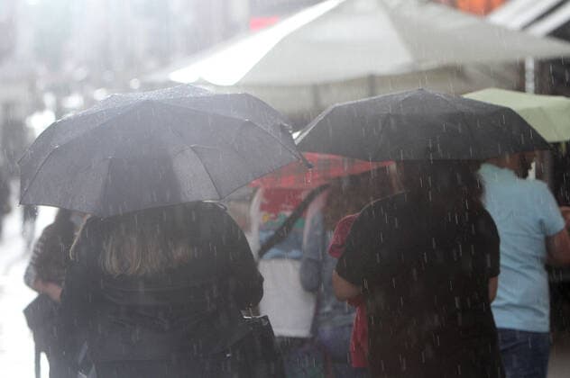 People walk with umbrellas during a rain shower in downtown Heidelberg, Baden Württemberg, Germany