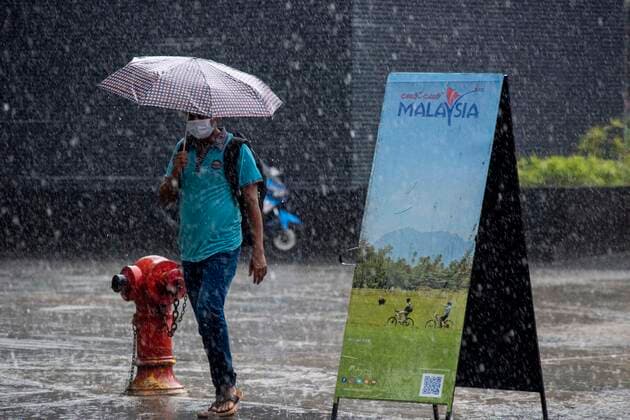 (210708) -- KUALA LUMPUR, July 8, 2021 -- A man wearing a face mask walks in the rain in Kuala Lumpur, Malaysia, July 8, 2021. Malaysia recorded a fresh high of 135 single-day death toll from COVID-19 on Thursday, bringing the total deaths to 5,903, according to the health ministry. Another 8,868 new infections were reported in the second-highest single-day tally since the outbreak, bringing the national total to 808,658. (Photo by Xinhua) MALAYSIA-KUALA LUMPUR-COVID-19-CASES ChongxVoonxChung